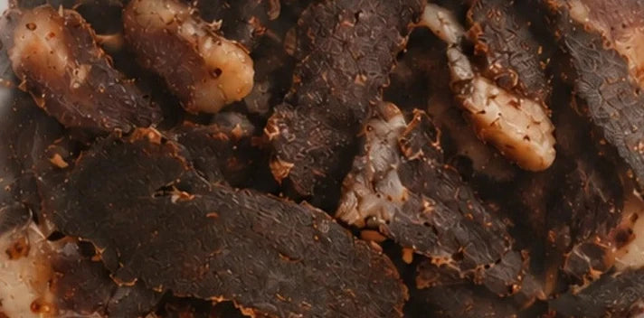 Barbeque biltong seen through the pack window: dark air-dried beef with visible seasoning