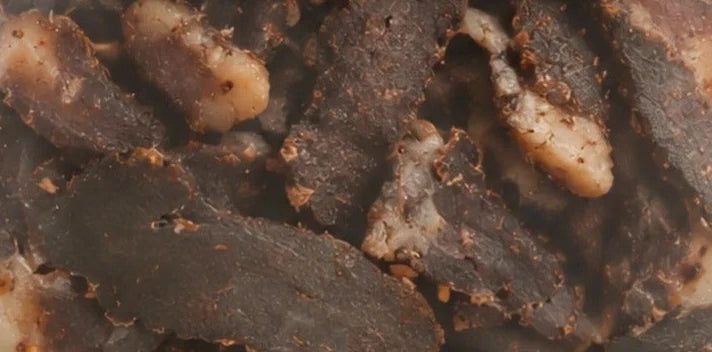 Traditional Hunters biltong seen through the pack window: dark air-dried beef with visible seasoning