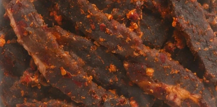 Peri-Peri biltong seen through the pack window: dark air-dried beef with visible seasoning
