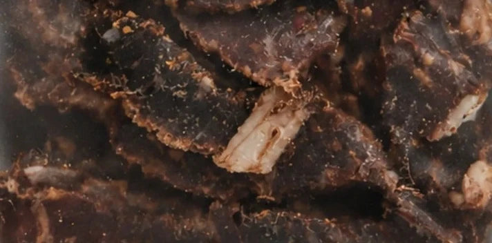 Chutney biltong seen through the pack window: dark air-dried beef with visible seasoning