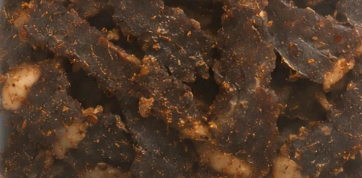 Honey Peri biltong seen through the pack window: dark air-dried beef with visible seasoning
